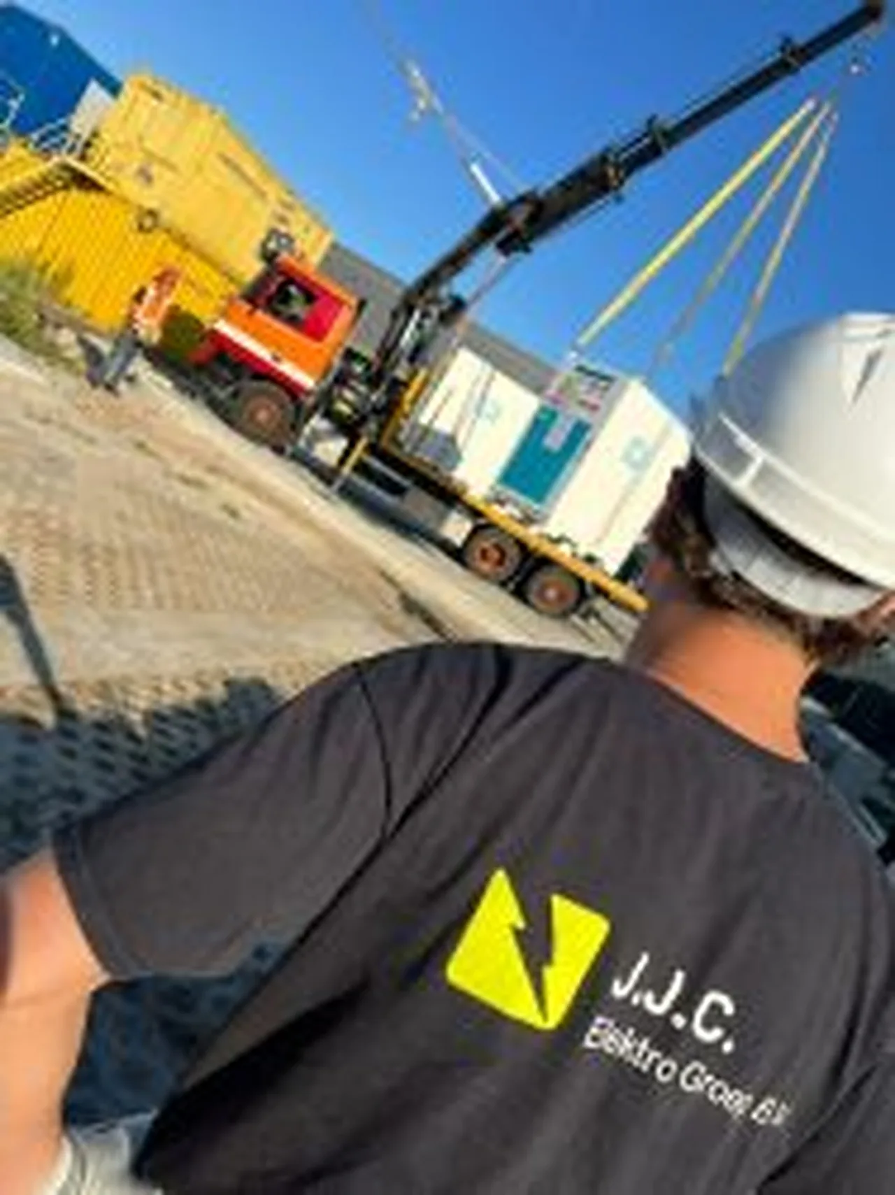Monteur van J.J.C. op een bouwplaats met kraan en bouwkeet
